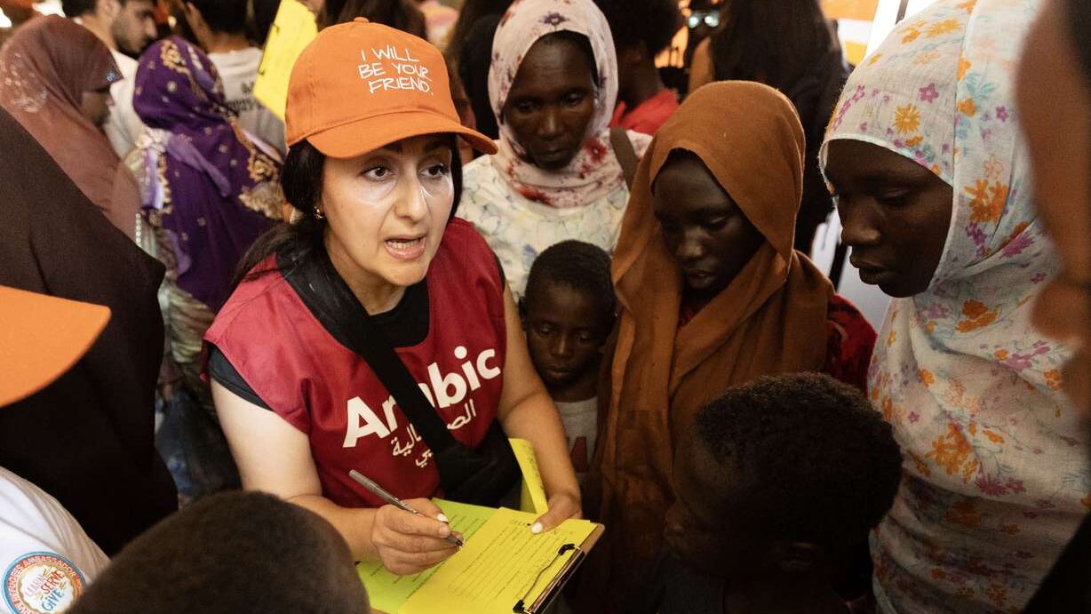 Volunteer Marwa Najjar helps a family fill out the paperwork to get backpacks and school supplies f...