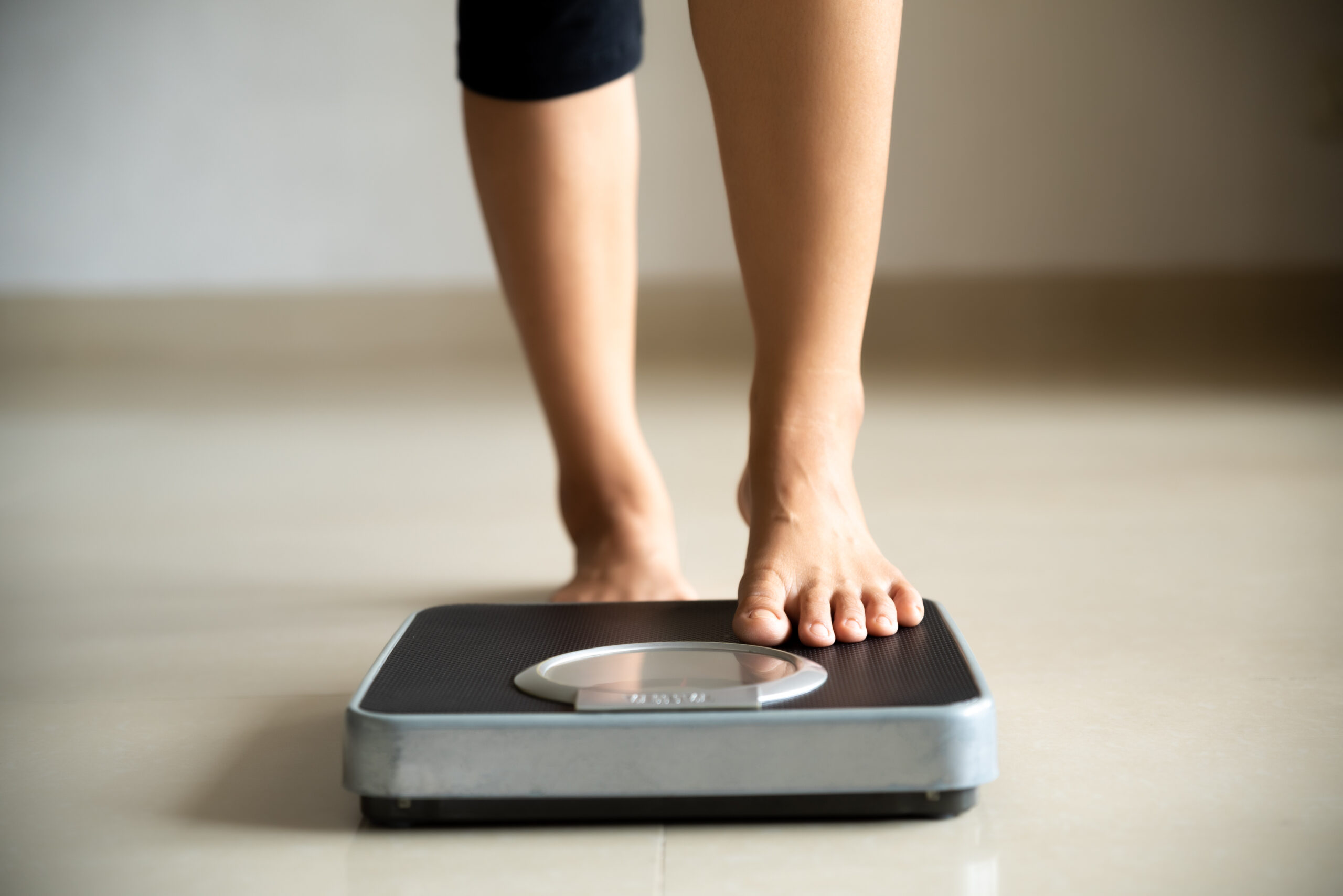 Female leg stepping on weigh scales. Healthy lifestyle, food and sport concept....