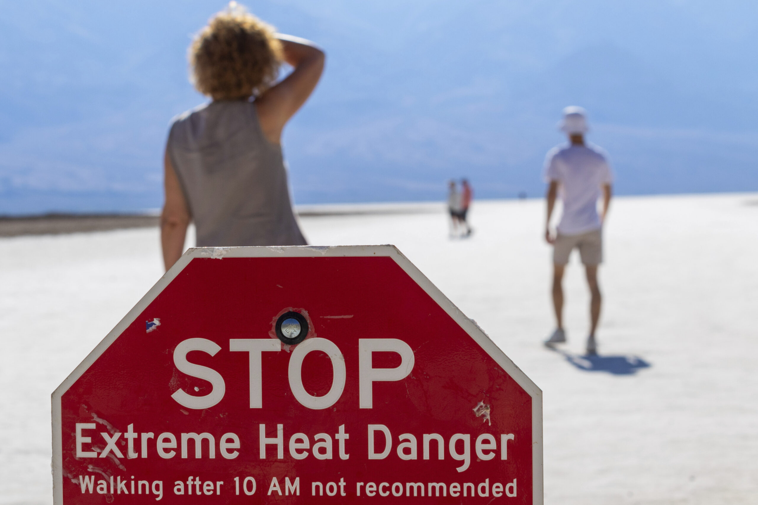 FILE - A person wipes sweat from their brow at Badwater Basin in Death Valley National Park, Calif....