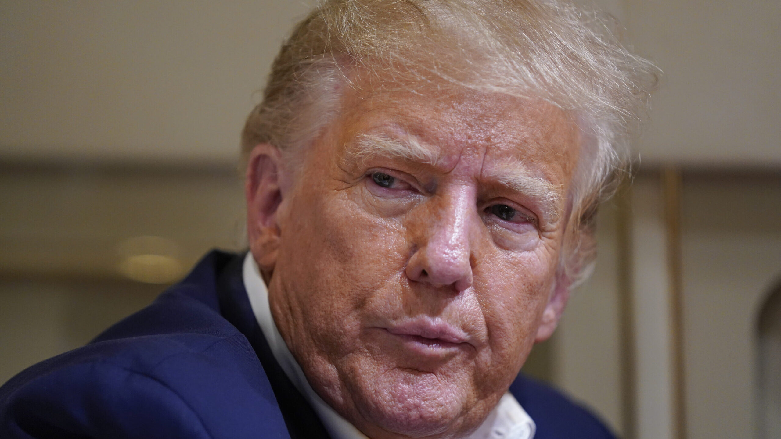 Former President Donald Trump listens as he speaks with reporters while in flight on his plane afte...