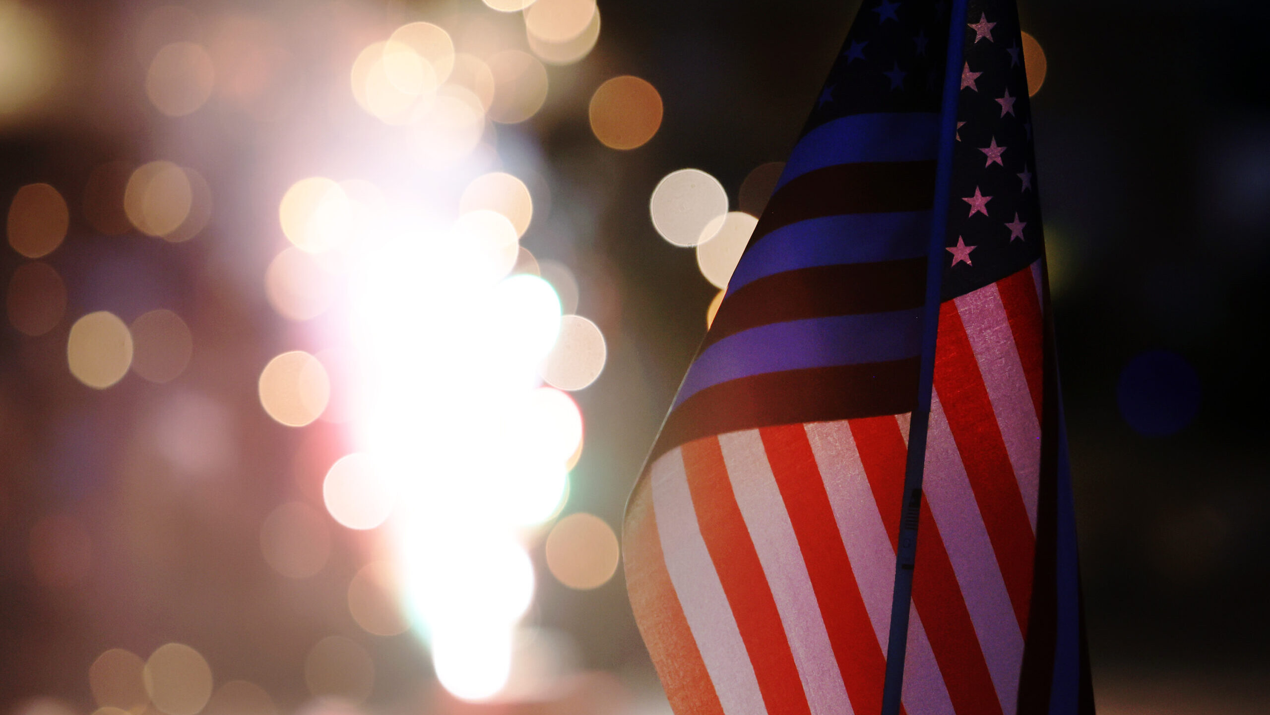 A small American flag is illuminated by fireworks on Monday, July 4, 2022....