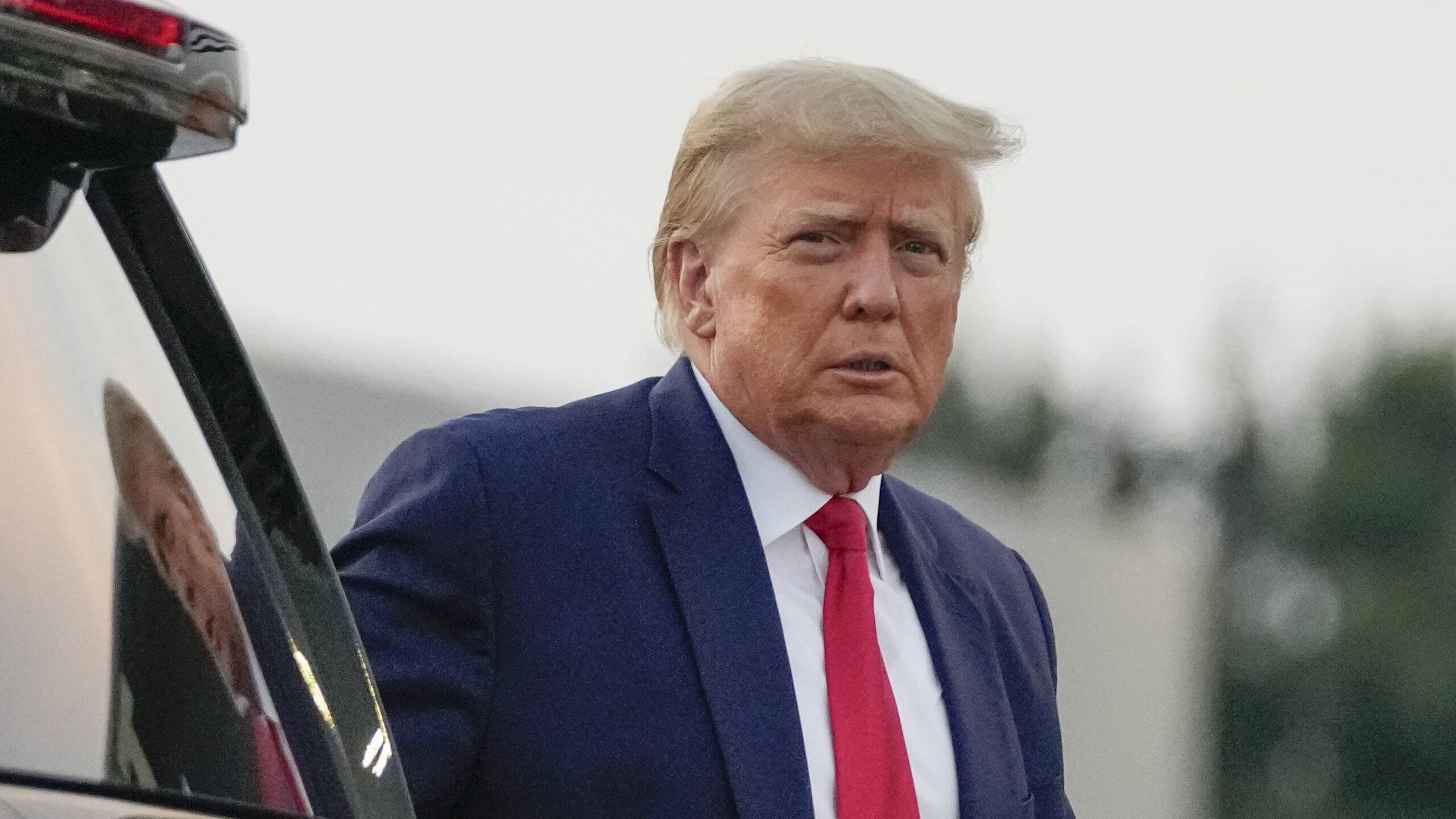 Image of former President Donald Trump walking to speak with reporters before departure from Hartsf...