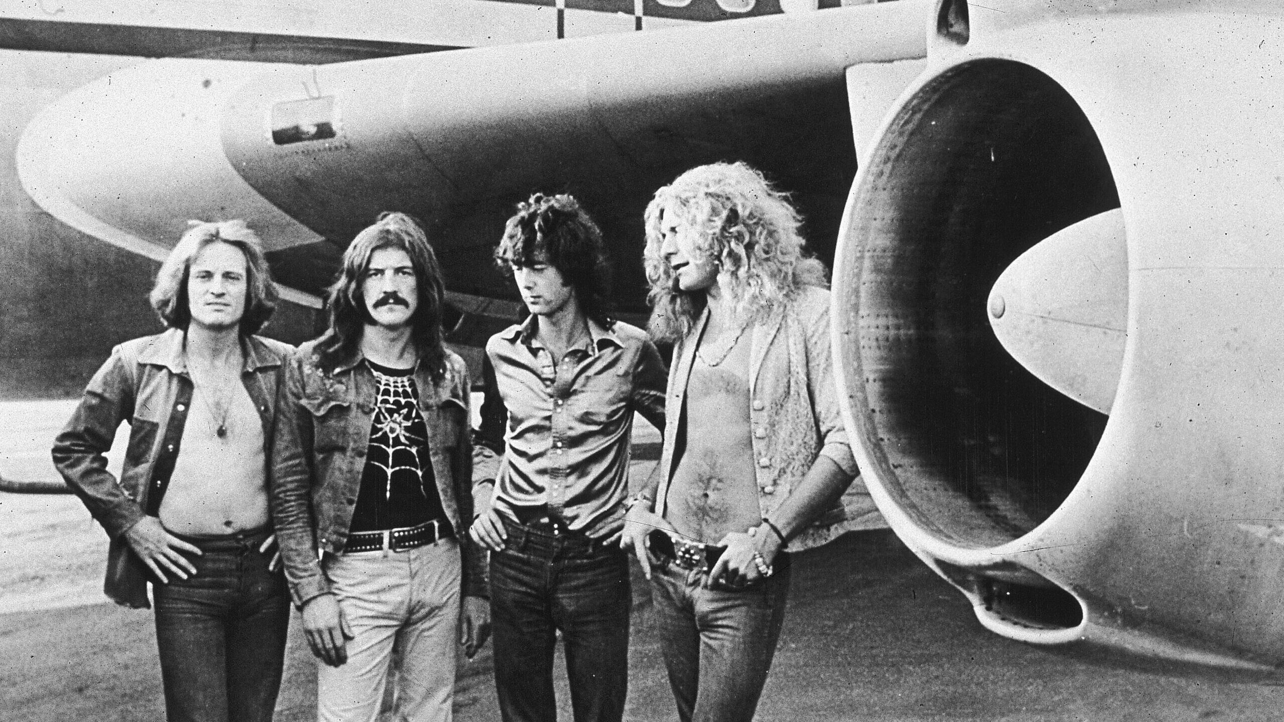 The members of Led Zeppelin pose in front of their private jet, a classic dad rock band...