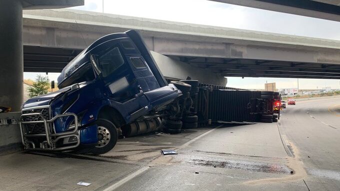 The semi truck is pictured after the accident, only the front two wheels remain on the ground....