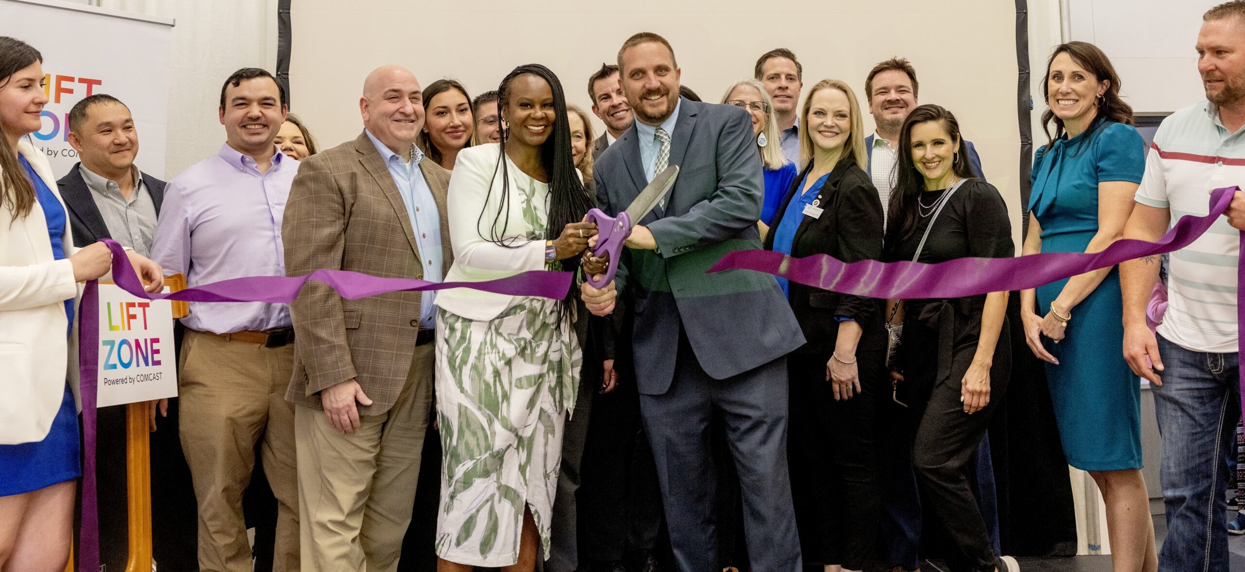 A group of people cut a purple ribbon...