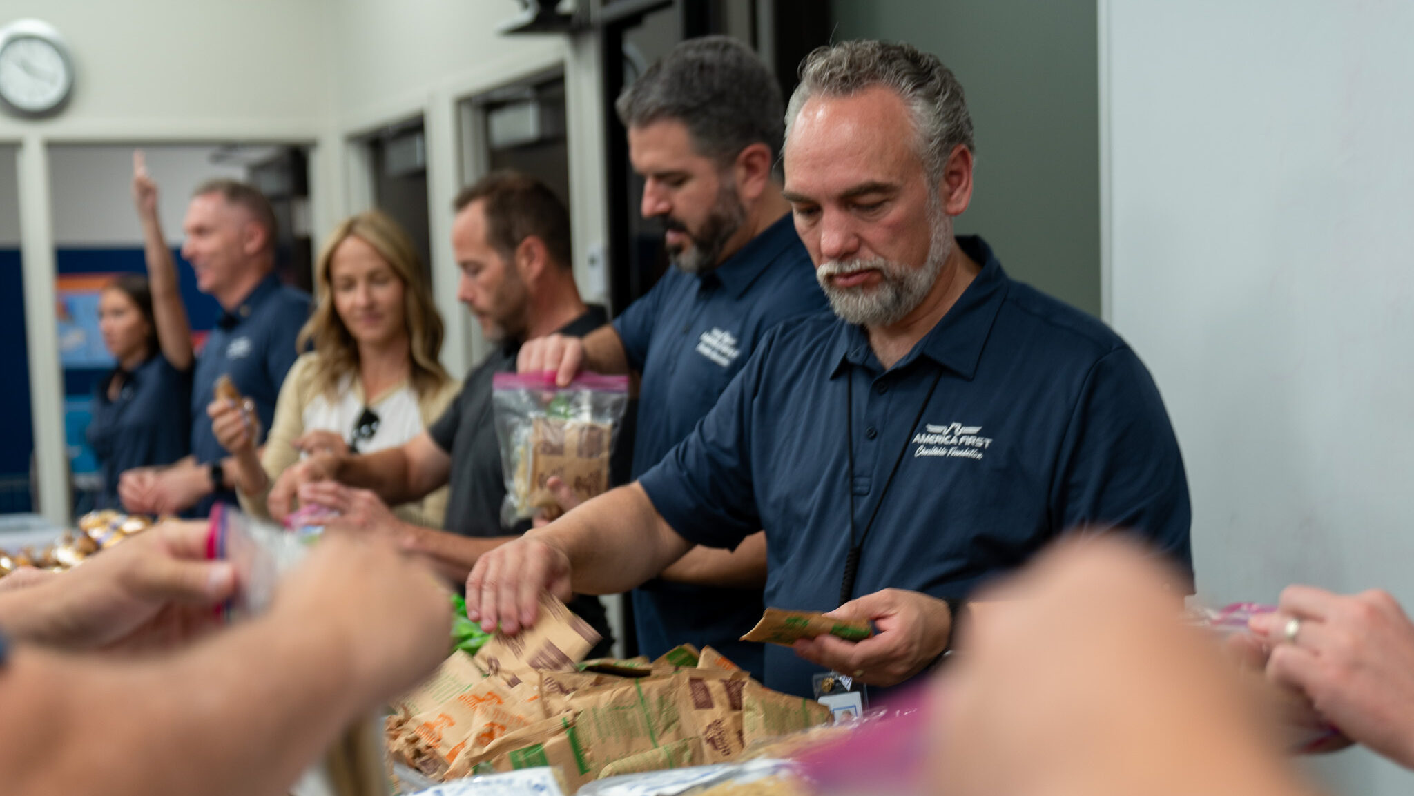 America First Credit Union workers assemble meal kits, called 'pantry packs', for children in need....