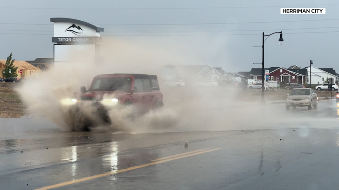 A vehicle splashes through water that quickly pooled on Herriman City streets when rain started fal...